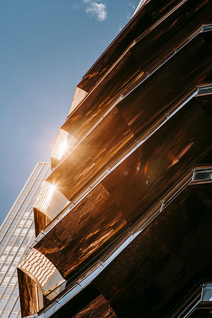 From below exterior of contemporary business office with geometric design and unusual architecture located against blue sky under sunlight in city